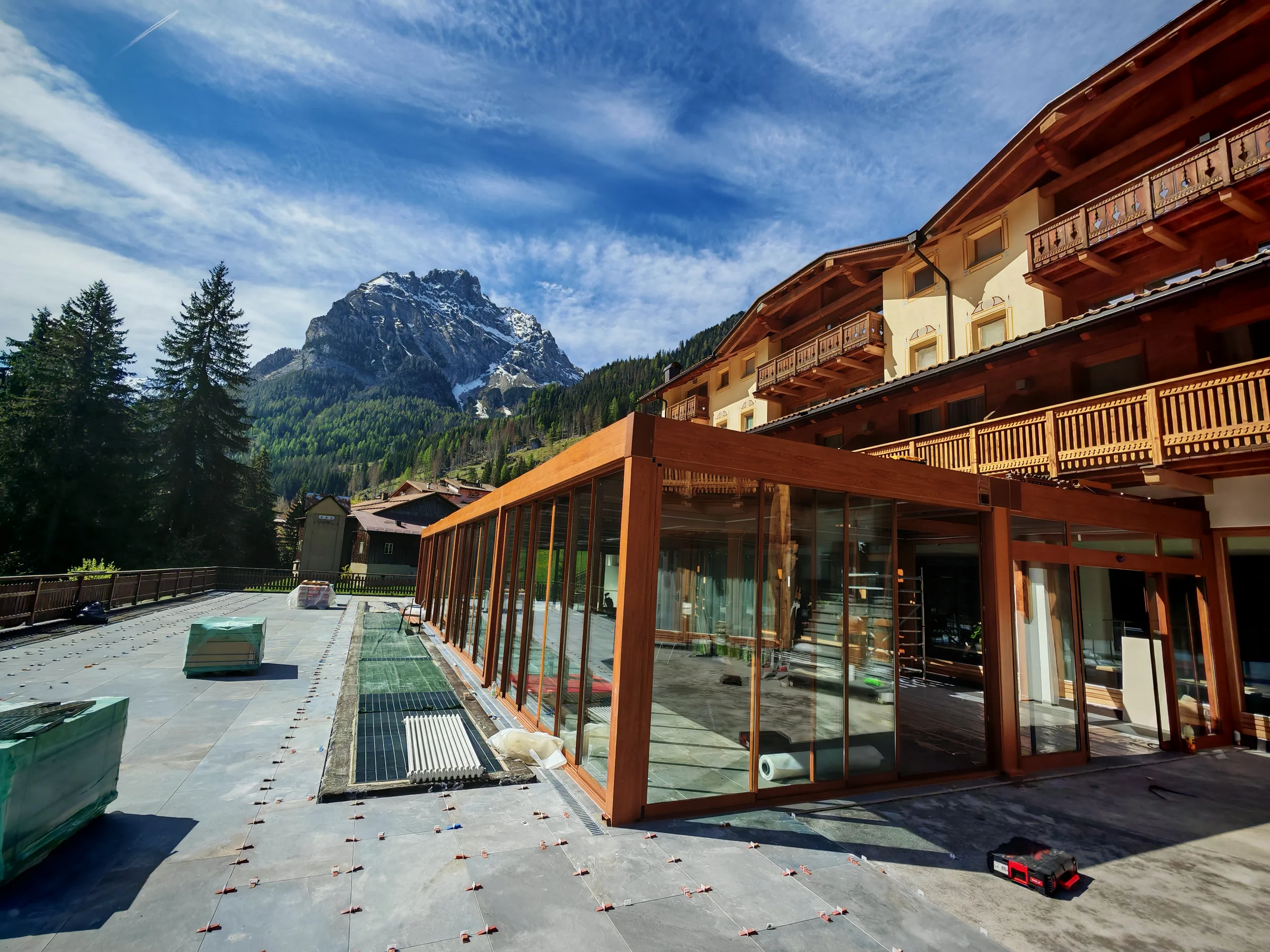 Extindere vitrată din sticlă și profile în finisaj lemn, alipită unui hotel alpin