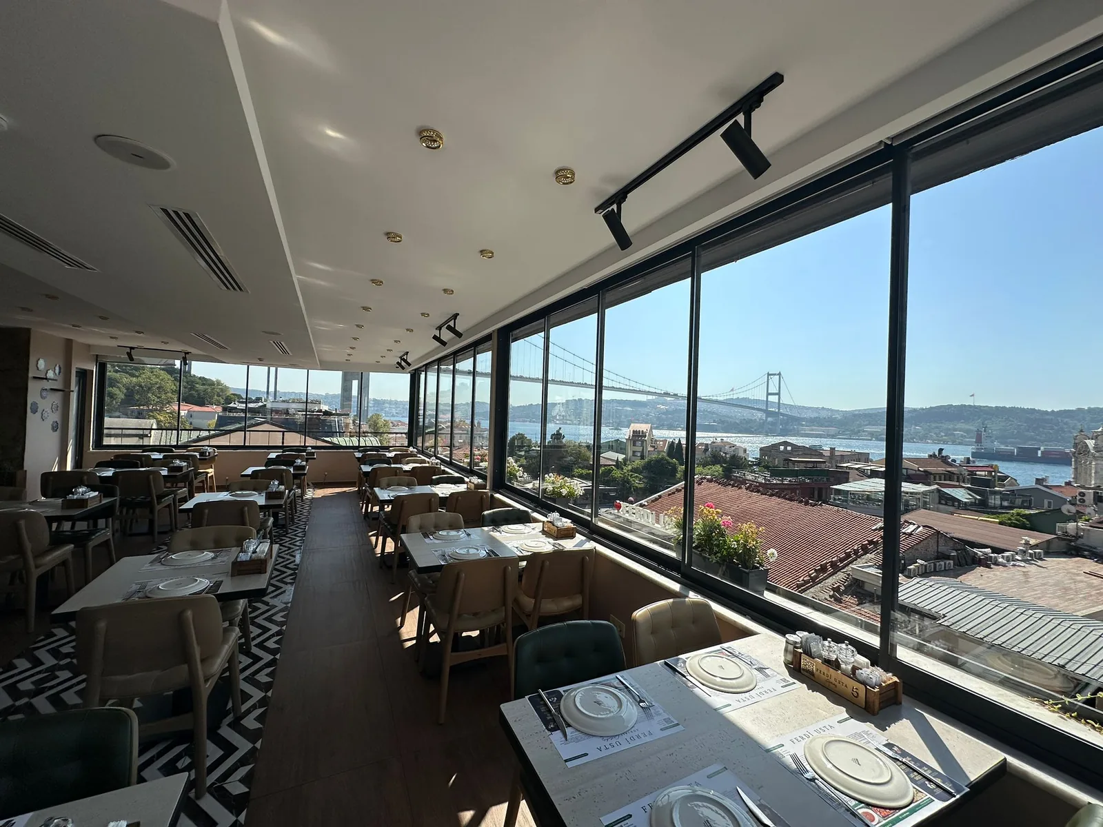 Restaurant cu fațadă din sticlă glisantă deschisă spre apă; panourile strânse lateral în pachet